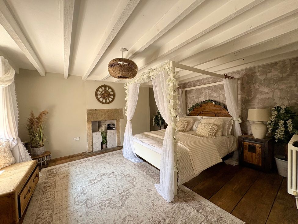 A bedroom with a canopy bed and a lamp at Coupling Cottage in Belper