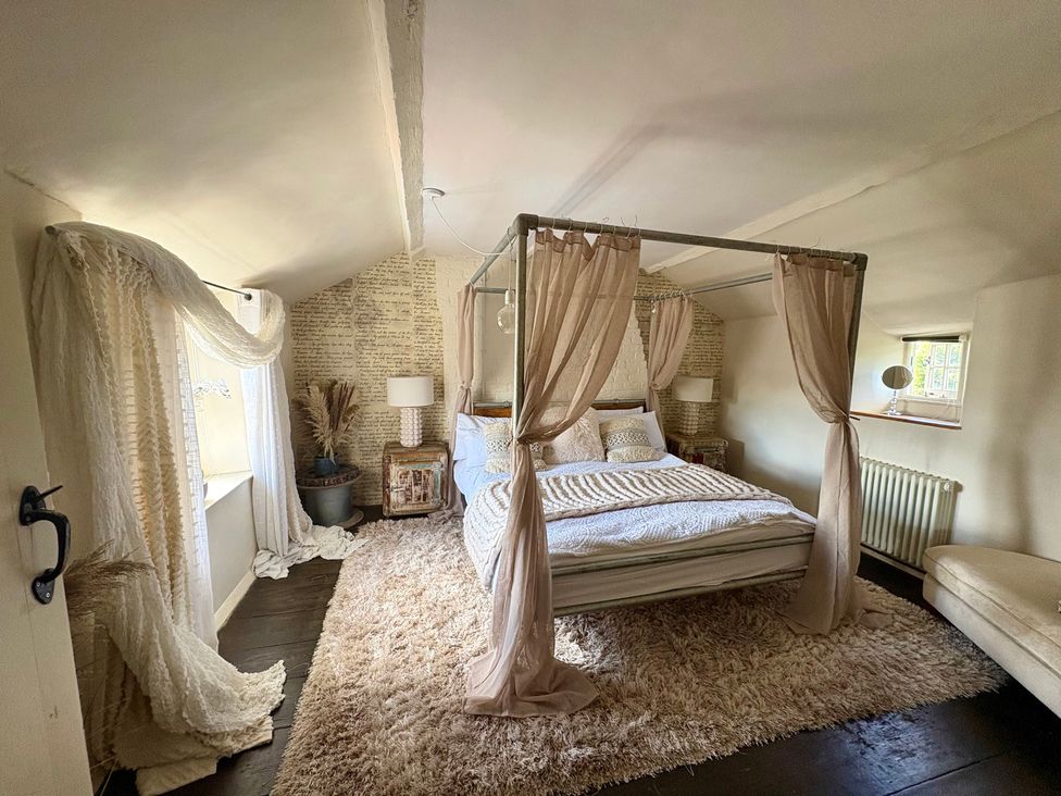 A bedroom with a four-poster bed and a plant at Coupling Cottage in Belper