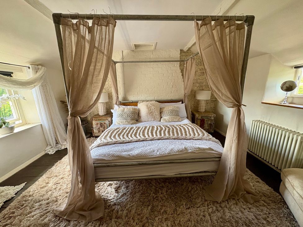 A bedroom with a canopy bed and a lamp at Coupling Cottage in Belper
