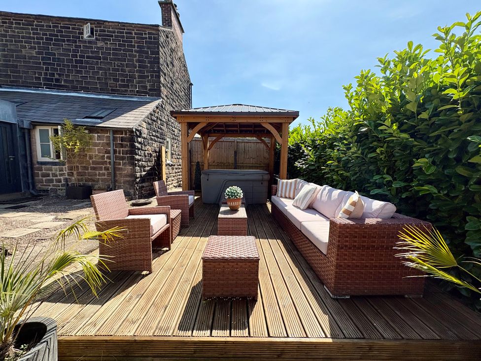 A patio with outdoor furniture and a hot tub at Coupling Cottage in Belper