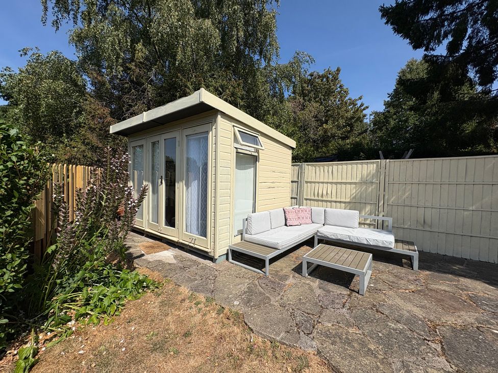A garden with a shed and outdoor seating area at Coupling Cottage in Belper