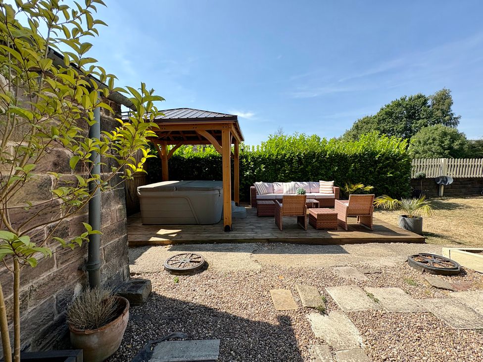 A garden with a hot tub and seating area at Coupling Cottage Belper