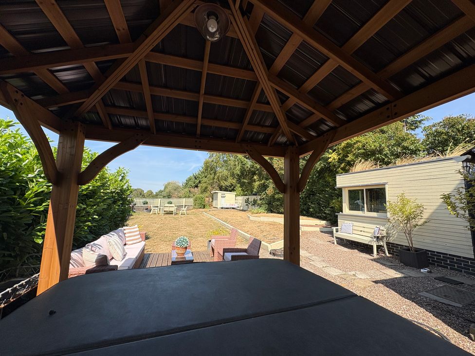 A garden view with a pergola and seating area at Coupling Cottage in Belper