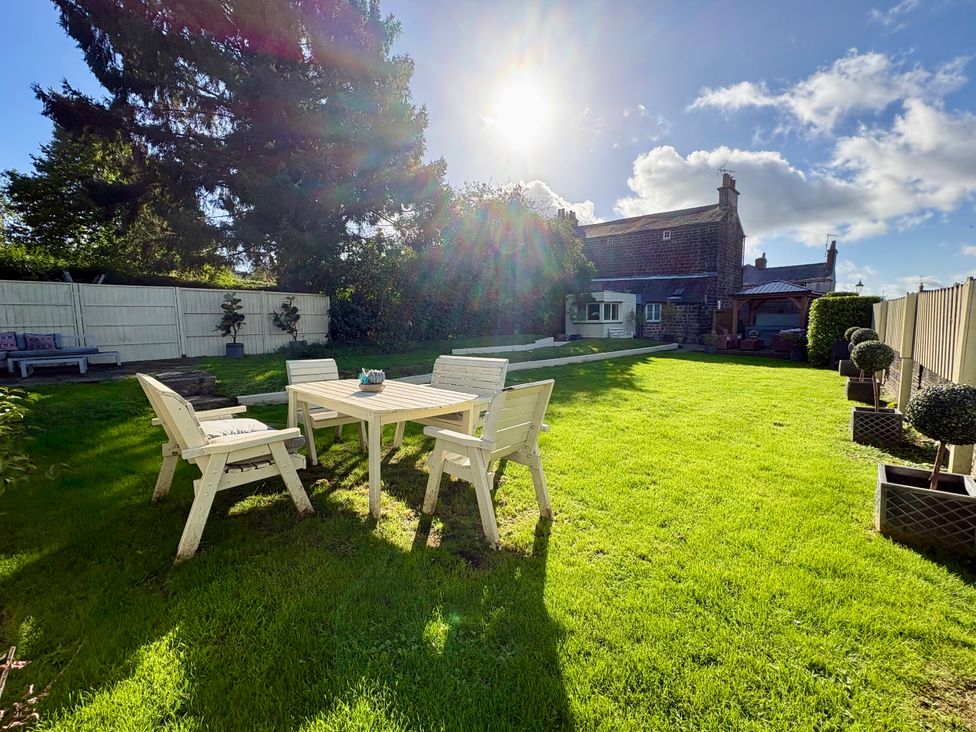 A garden with a table and chairs at Coupling Cottage in Belper