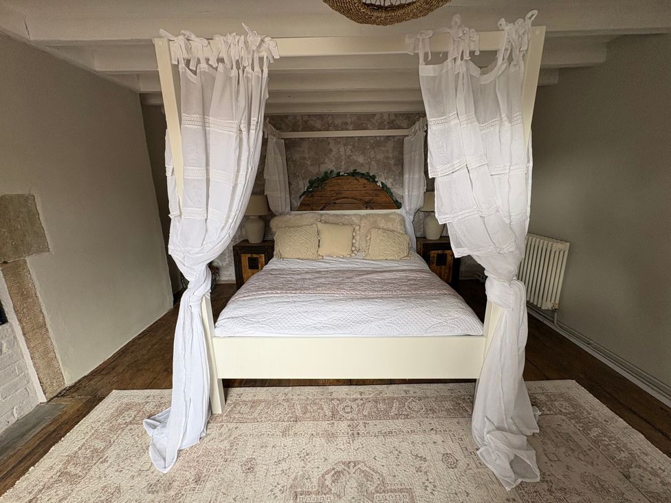 A bedroom with a four-poster bed and pillows at Coupling Cottage in Belper