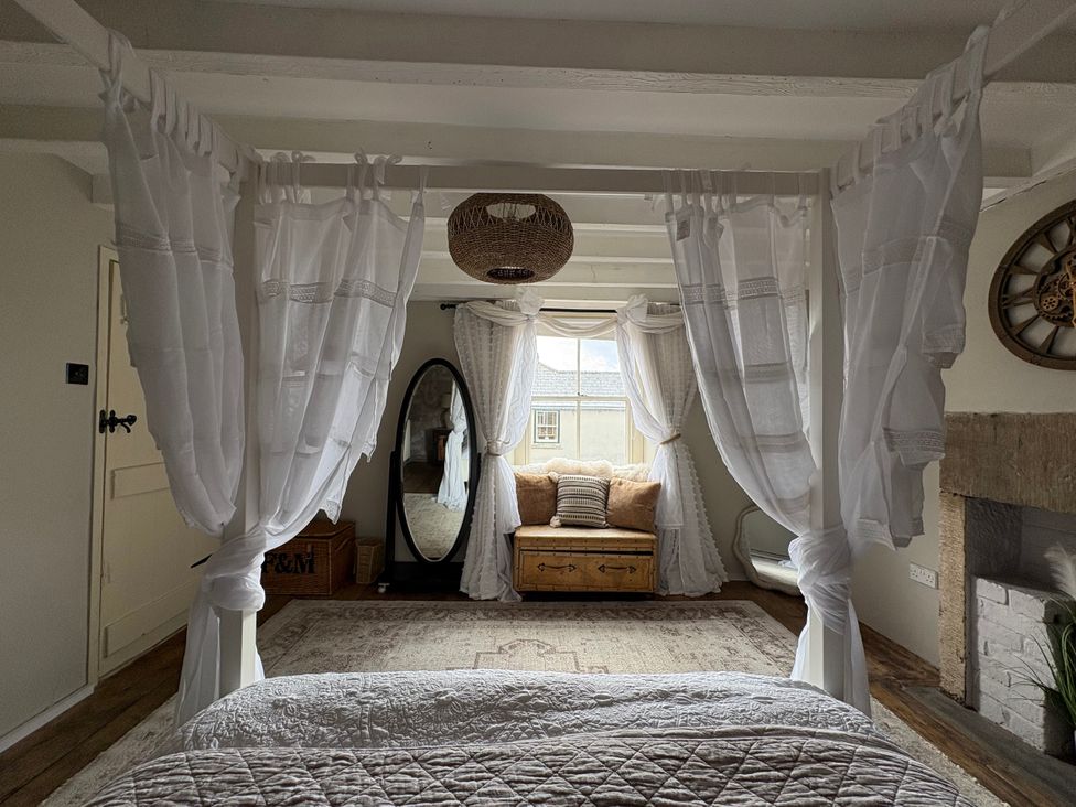 A bedroom with a sofa and mirror in view at Coupling Cottage Belper