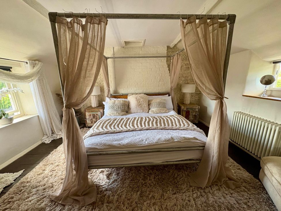 A bedroom with a canopy bed and side tables at Coupling Cottage in Belper