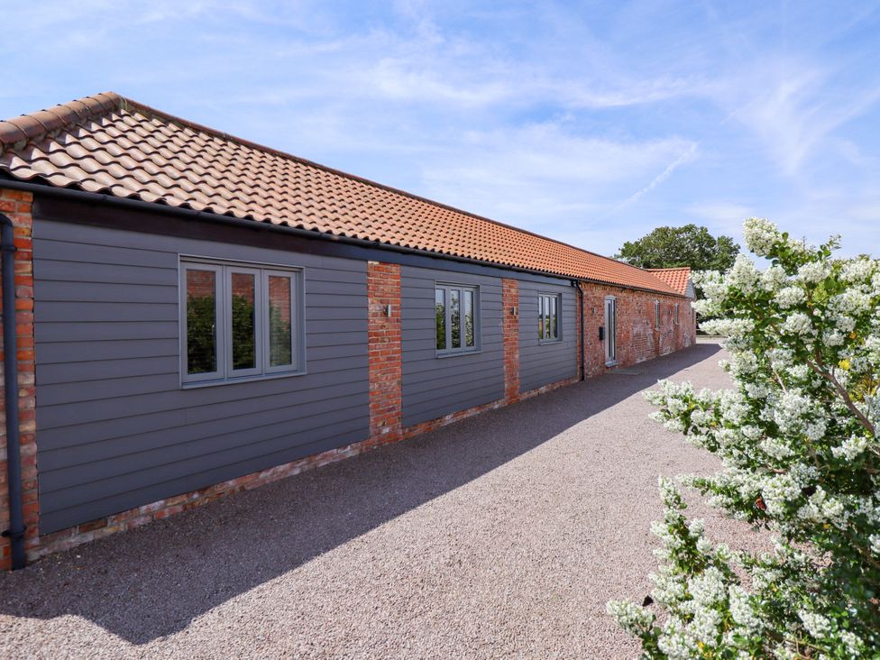 An exterior view of a grey building with windows and a gravel pathway at The Stables in Wrangle near Old Leake