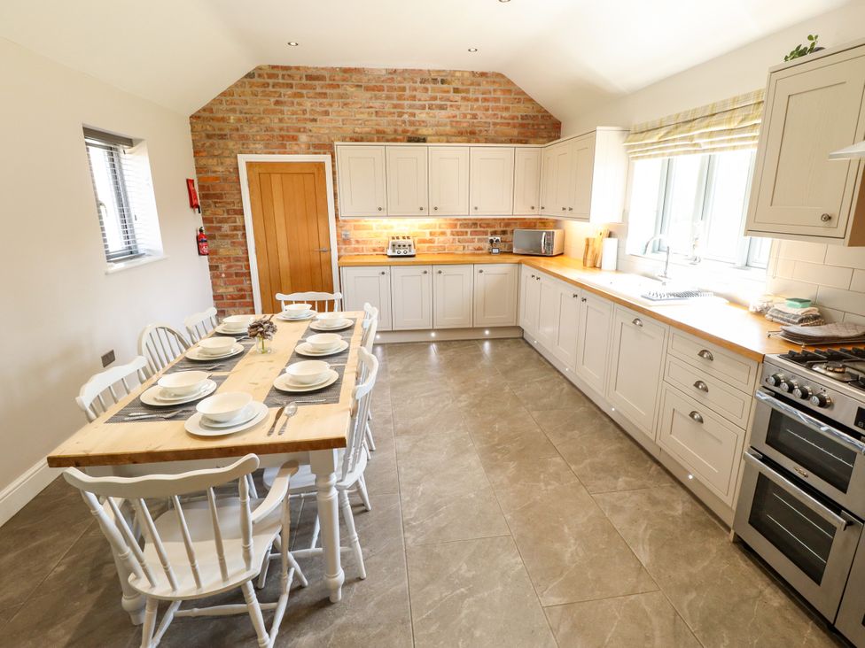 A kitchen with a dining table and appliances at The Stables in Wrangle near Old Leake