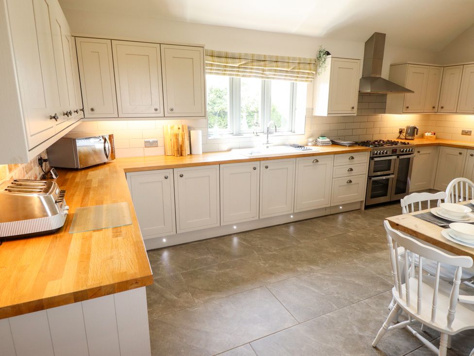 A kitchen with cabinets, appliances, and dining area at The Stables in Wrangle near Old Leake