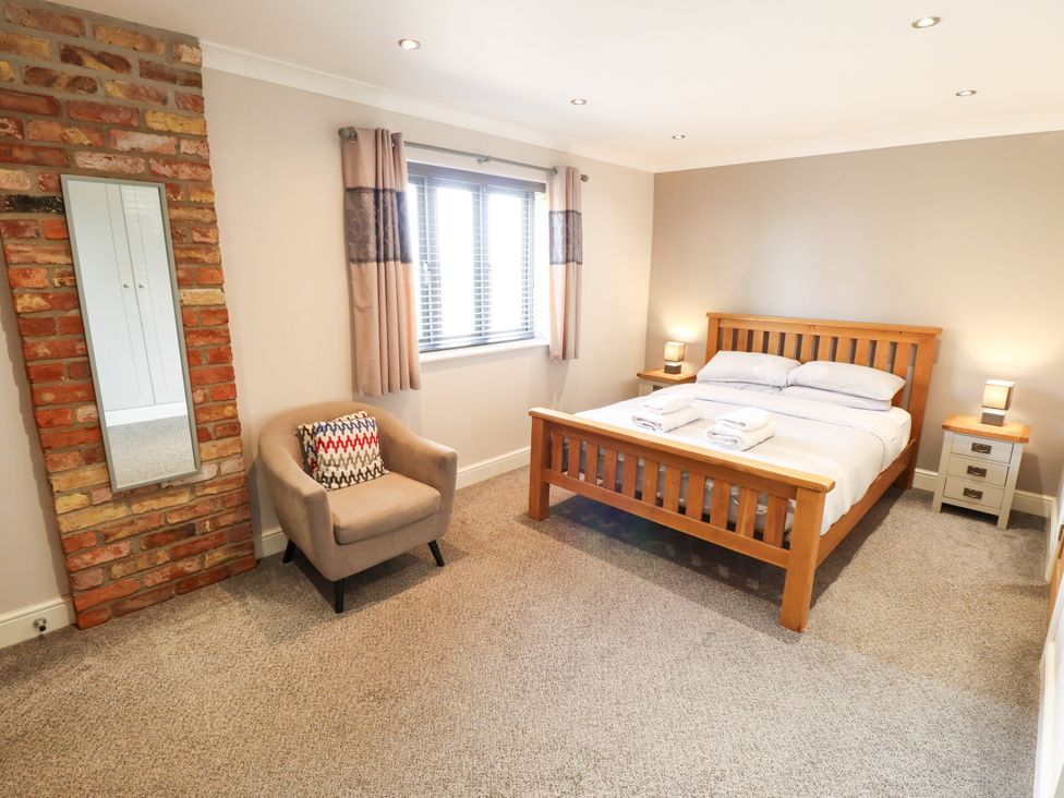 A bedroom with a bed, chair, and window at The Stables in Wrangle near Old Leake