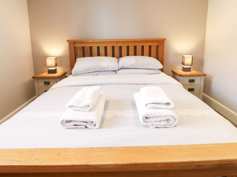A bedroom with a wooden bed and towels on the bed at The Stables in Wrangle near Old Leake