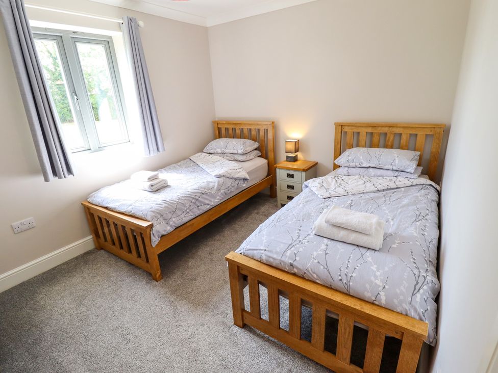A bedroom with two beds and a bedside table at The Stables in Wrangle near Old Leake