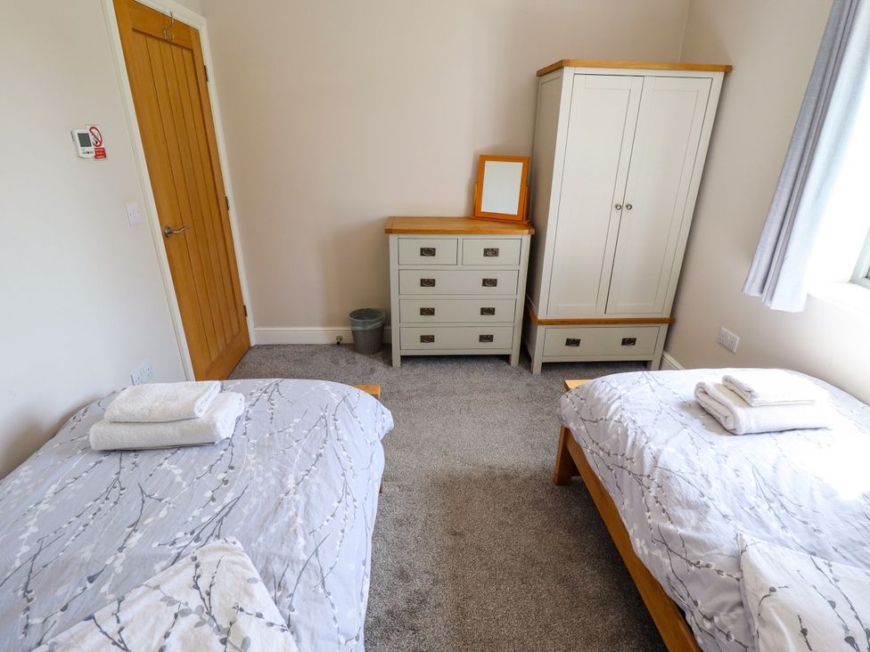 A bedroom with two beds and a wardrobe at The Stables in Wrangle near Old Leake