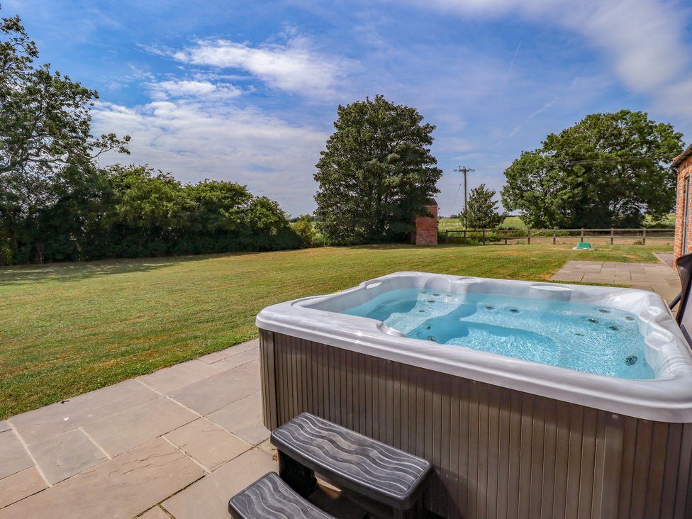 A hot tub on a patio overlooking a garden at The Stables in Wrangle near Old Leake