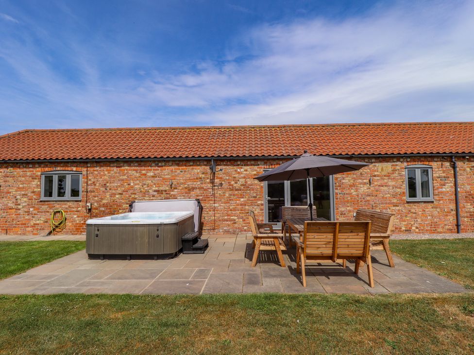 An outdoor area with a hot tub and dining set at The Stables in Wrangle near Old Leake
