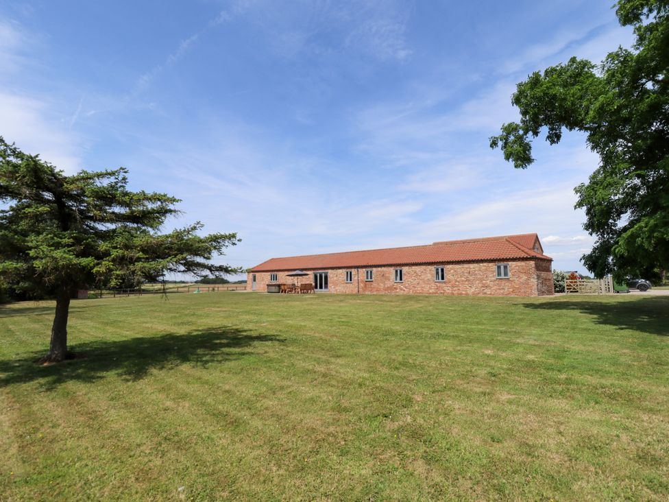 A building with a lawn and trees at The Stables in Wrangle near Old Leake