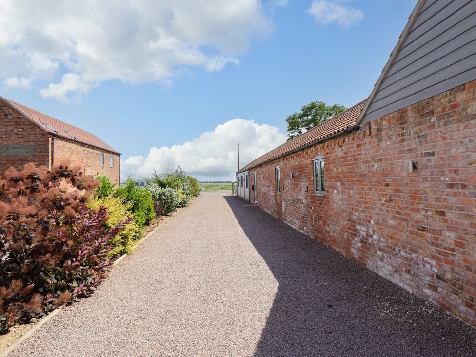 An outdoor area with brick buildings and a gravel path at The Stables in Wrangle near Old Leake