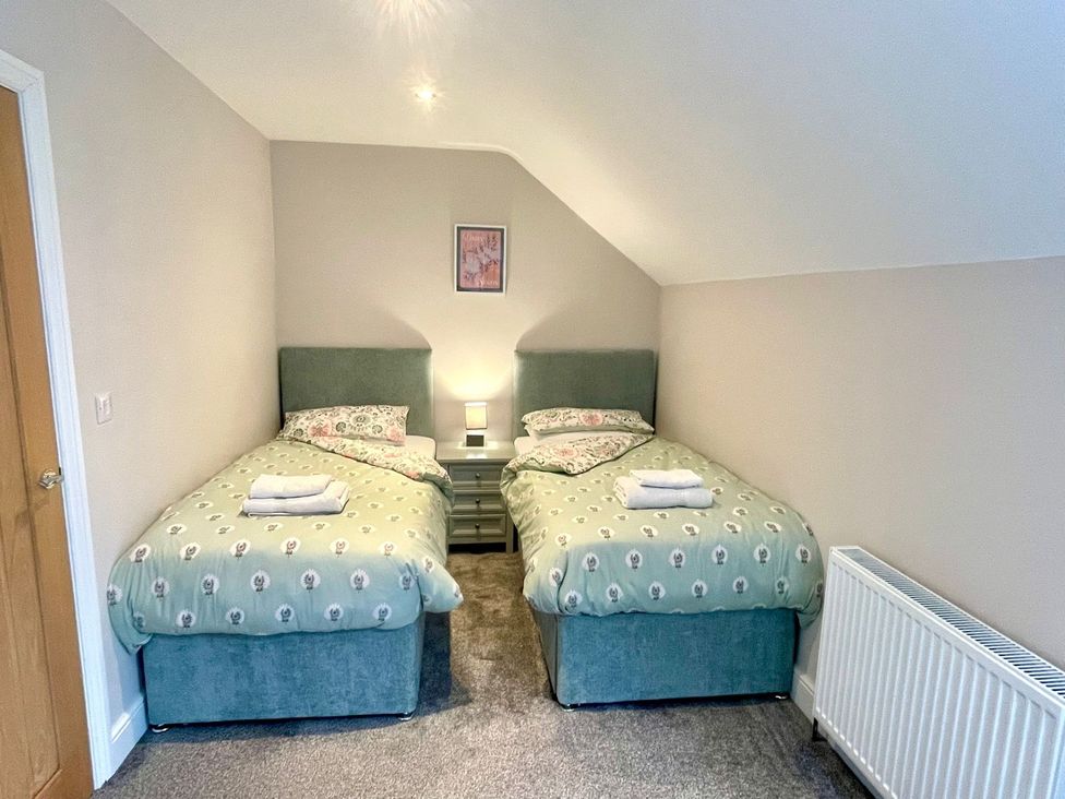 A bedroom with two beds and a bedside table at Acacia Barn in Wrangle near Friskney