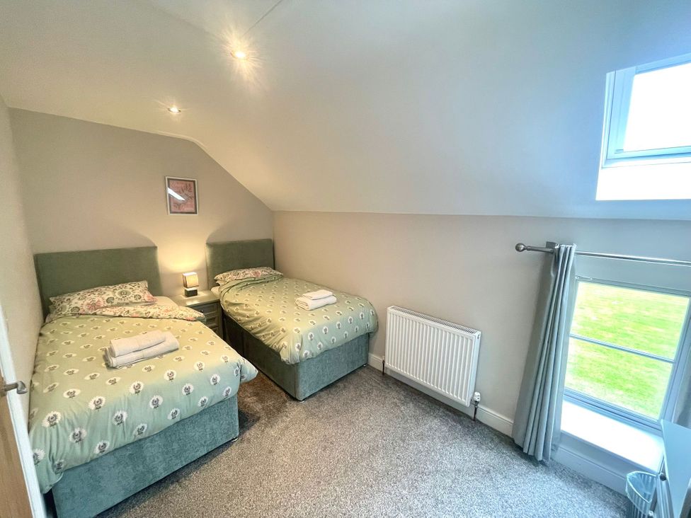 A bedroom with two beds and a window at Acacia Barn in Wrangle near Friskney