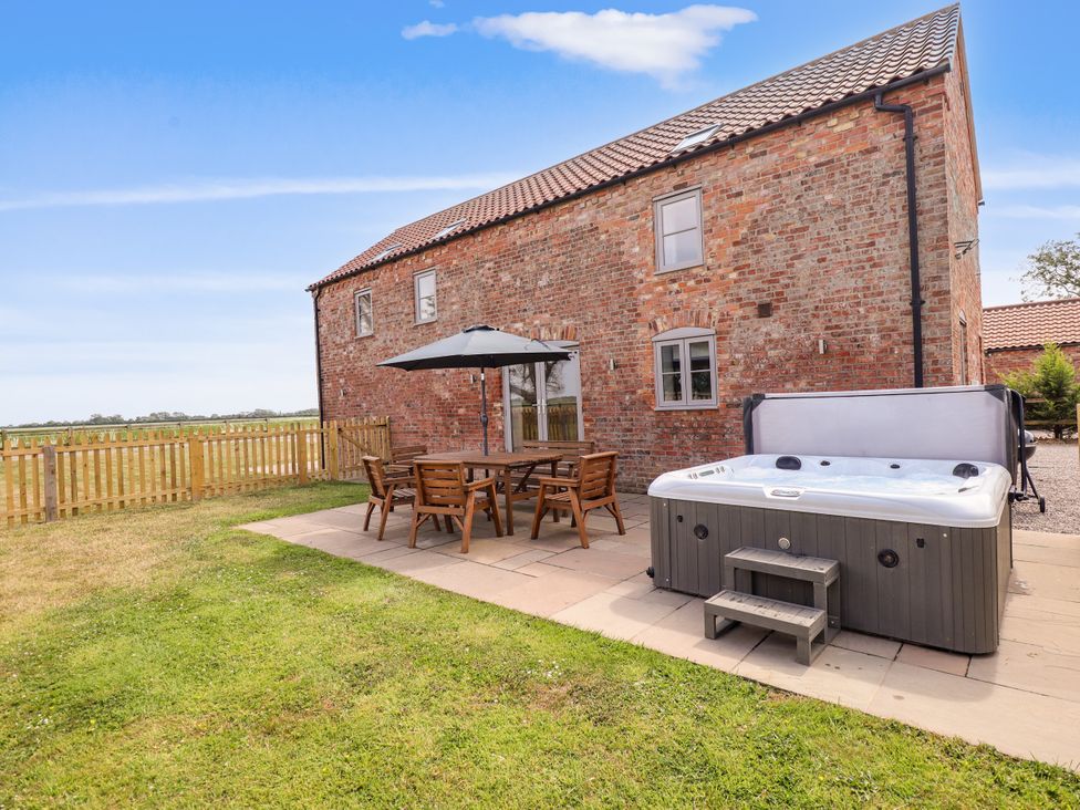 An outdoor area with a hot tub and a dining set at Acacia Barn in Wrangle near Friskney