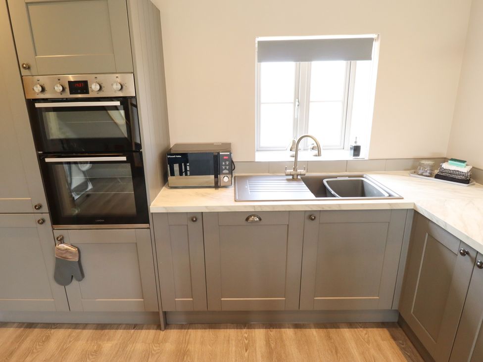 A kitchen with an oven, microwave, sink, and countertop at Acacia Barn Wrangle near Friskney