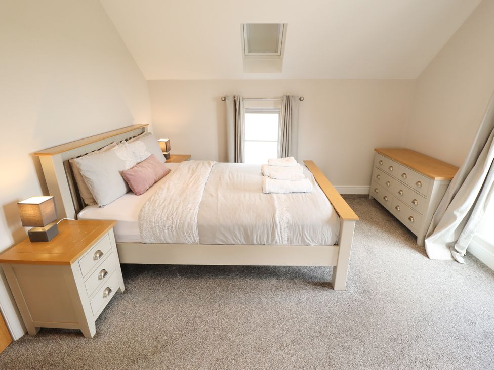 A bedroom with a bed, bedside table, and drawer unit at Acacia Barn Wrangle near Friskney