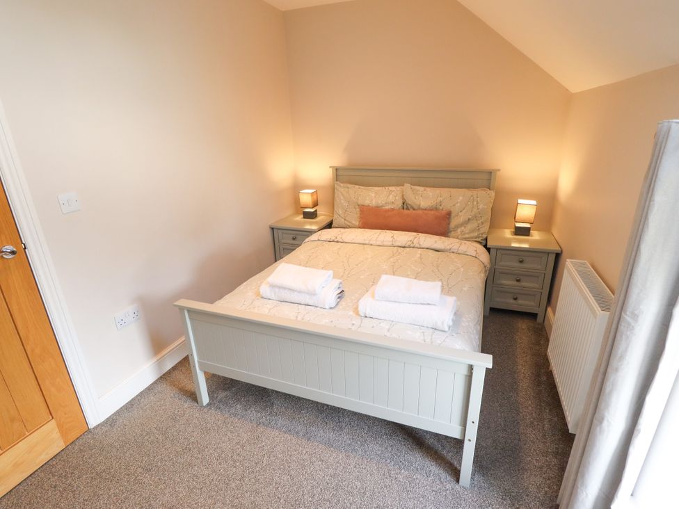 A bedroom with a bed and nightstands at Acacia Barn in Wrangle near Friskney