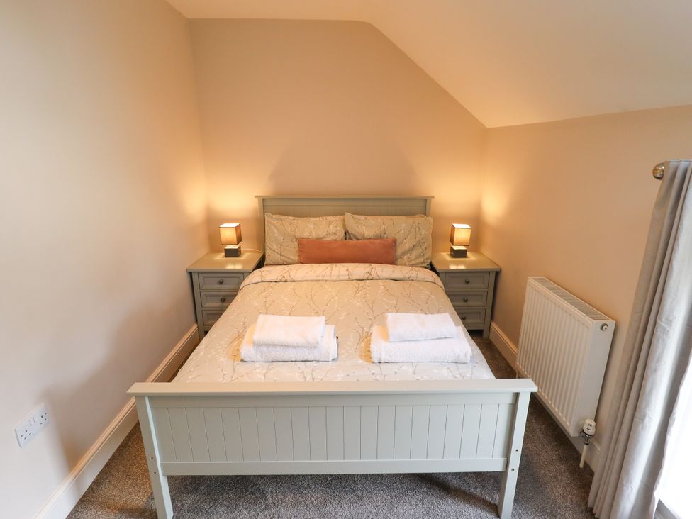 A bedroom with a bed and bedside tables at Acacia Barn near Friskney