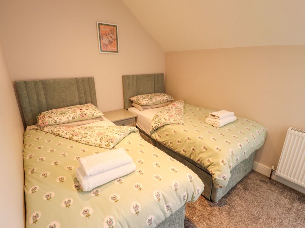 A bedroom with two beds and a bedside table at Acacia Barn in Wrangle near Friskney