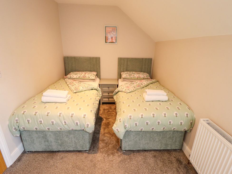 A bedroom with two beds and a bedside table at Acacia Barn in Wrangle near Friskney