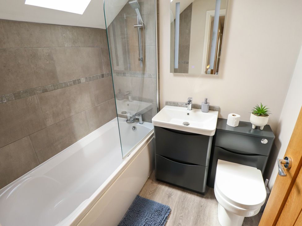 A bathroom with a bathtub, sink, toilet and mirror at Acacia Barn Wrangle near Friskney