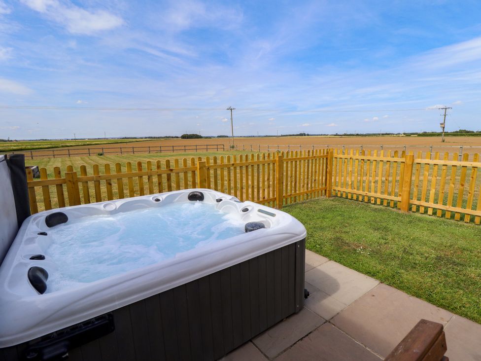 An outdoor area with a hot tub and a fenced field at Acacia Barn in Wrangle near Friskney