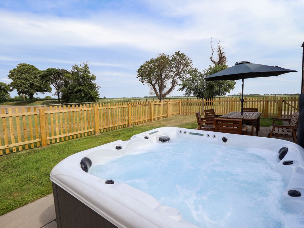 An outdoor area with a hot tub and seating at Acacia Barn Wrangle near Friskney
