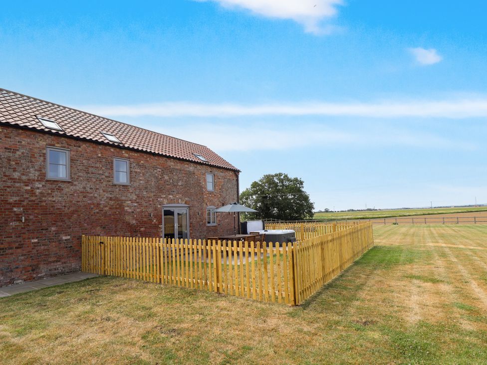 An outdoor area with a wooden fence around a seating area at Acacia Barn Wrangle near Friskney
