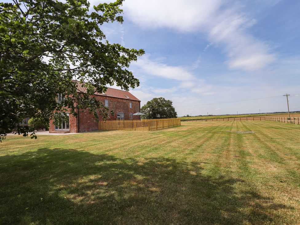 An outdoor area with a house and a fenced lawn at Acacia Barn Wrangle near Friskney