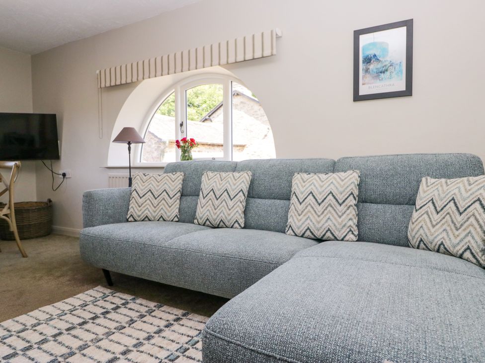 A living room with a sofa and a television at Windermere at the Graythwaite Estate near Hawkshead