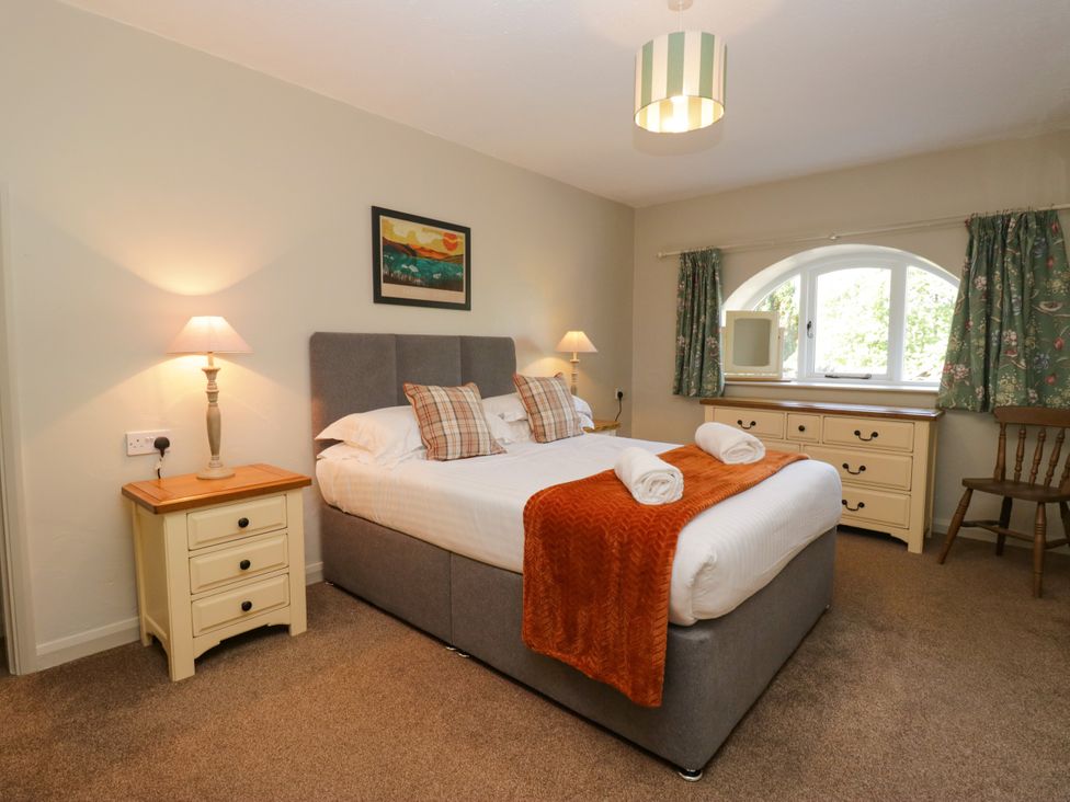 A bedroom with a bed, lamps, and dresser at Windermere at the Graythwaite Estate near Hawkshead