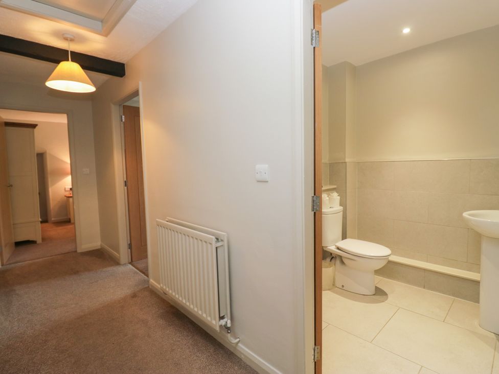 A hallway leading to a bathroom with a toilet and sink at Windermere at the Graythwaite Estate near Hawkshead