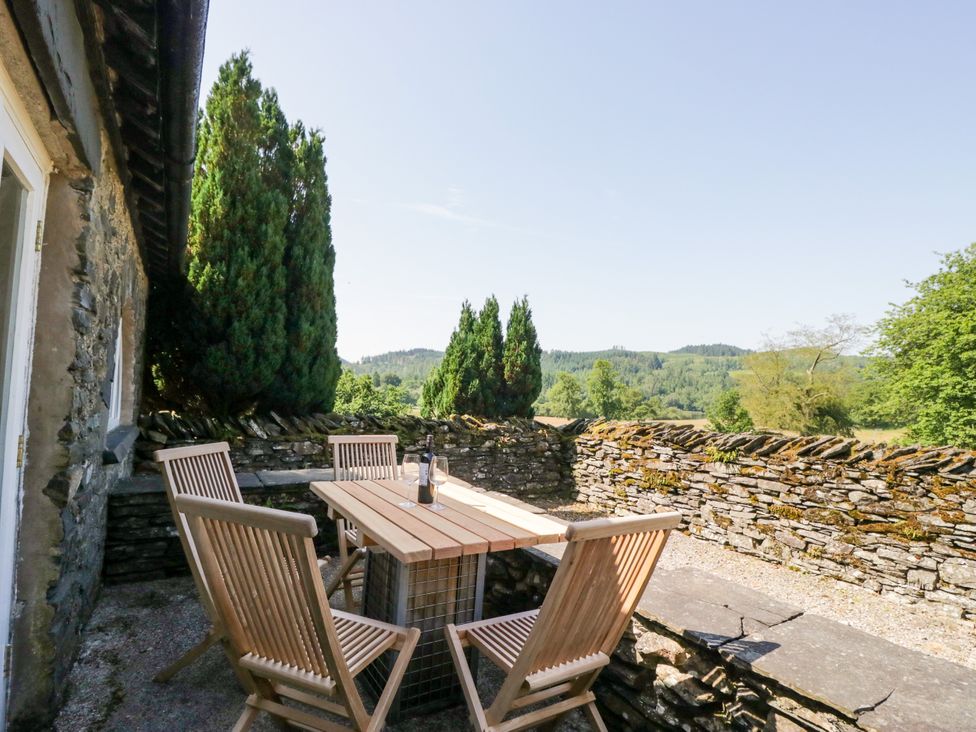 An outdoor seating area with a table and chairs overlooking a landscape at Windermere at the Graythwaite Estate near Hawkshead
