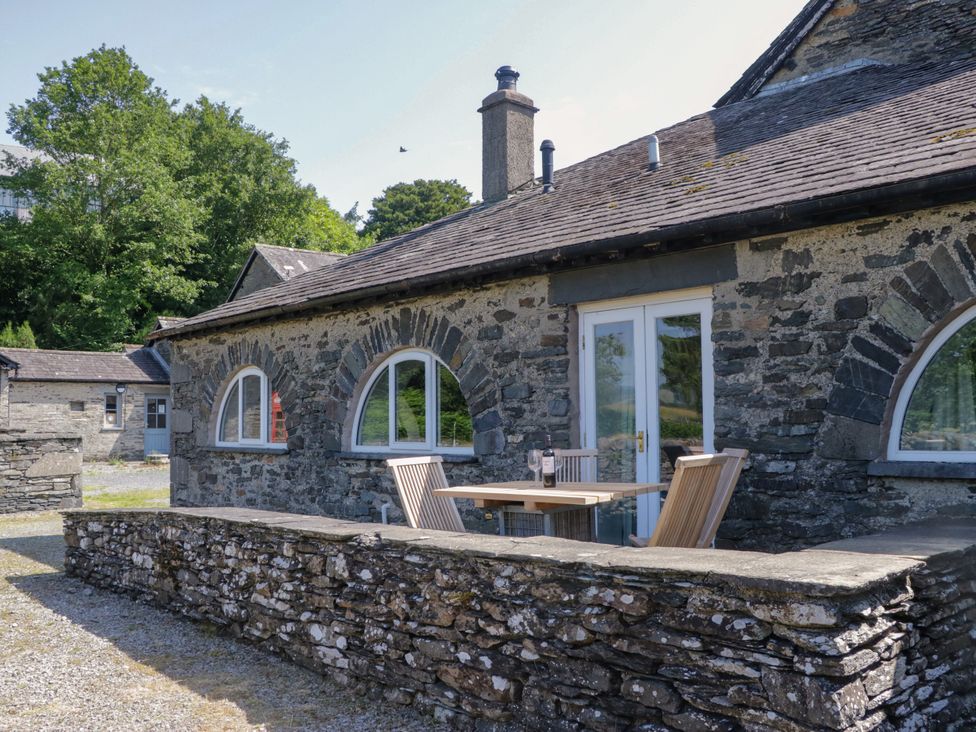 An outdoor area with a stone wall, table, and chairs at Windermere at the Graythwaite Estate near Hawkshead