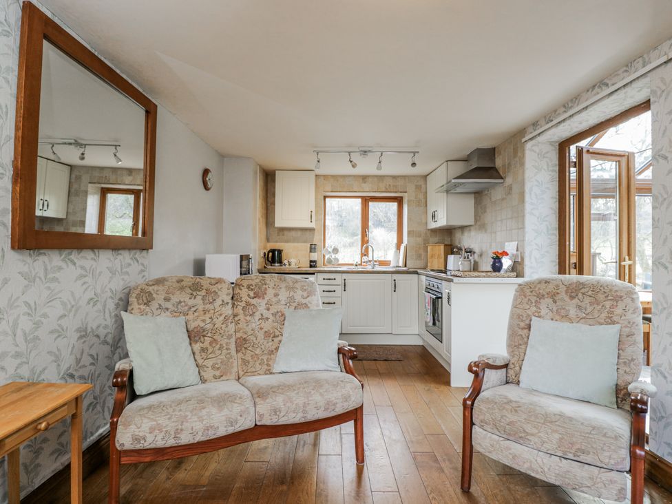 A living room with a sofa and kitchen area at Calcott Annexe in Whitchurch, Herefordshire