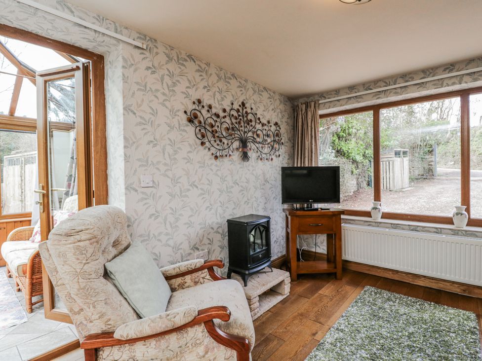 A snug with an armchair and television at Calcott Annexe in Whitchurch, Herefordshire