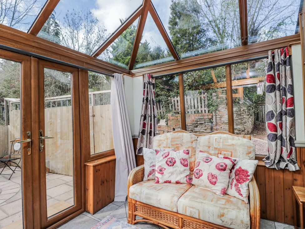 A conservatory with a sofa and large windows at Calcott Annexe in Whitchurch, Herefordshire
