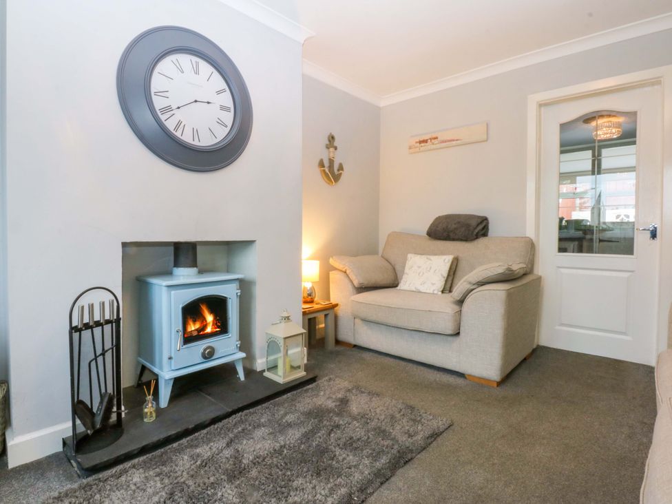 A living room with a fireplace and sofa at Pebbles Reach in Colwyn Bay