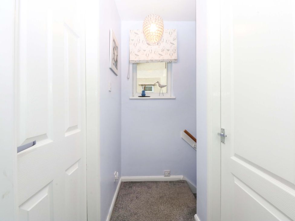 A hallway with a window and stairs at Pebbles Reach in Colwyn Bay