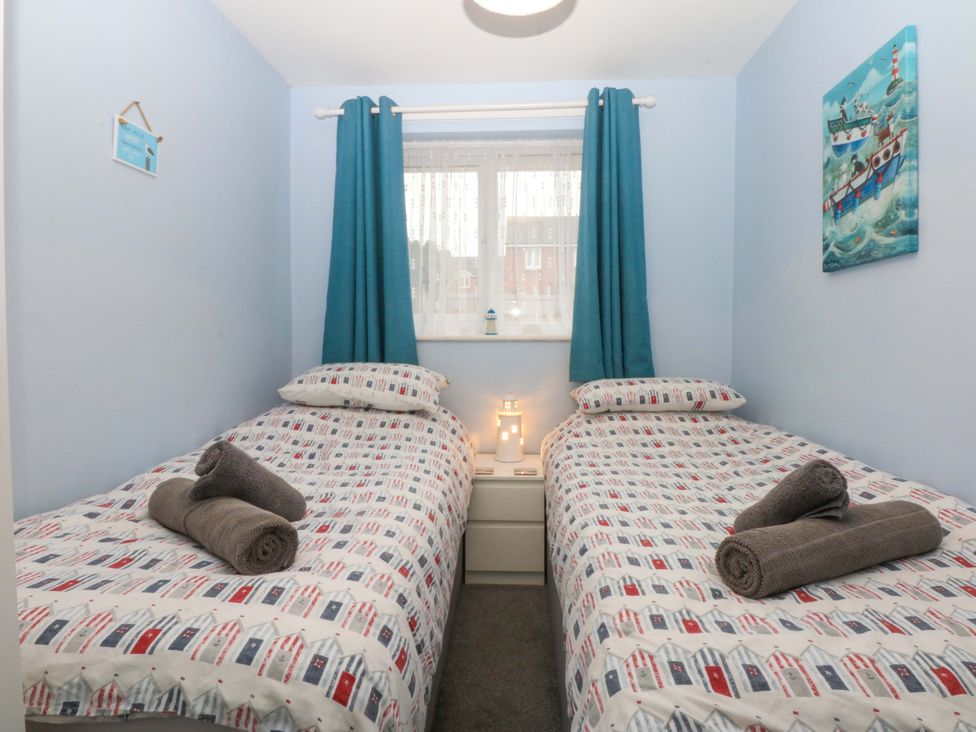 A bedroom with two beds and window at Pebbles Reach in Colwyn Bay