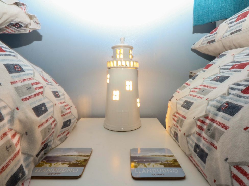 A bedside table with a lamp and coasters at Pebbles Reach in Colwyn Bay