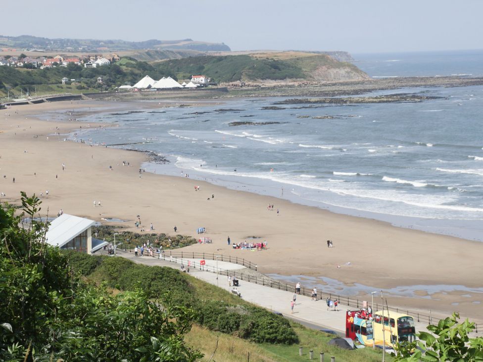 A beach with people walking and a bus at Jonstone Pines in Cayton Bay near Scarborough