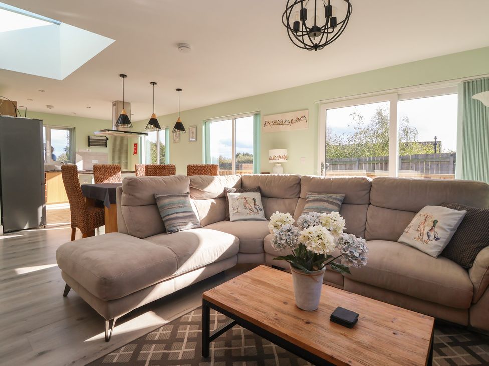 A living room with a sofa and a wooden table at Bluebell Wood in Brandesburton